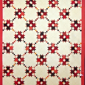 May include: A book cover featuring a red and black patchwork quilt design on a white background. The title of the book is "Square in a Square" and the author is "Jodi Barrows".