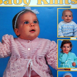 May include: A knitting pattern booklet for baby knits. The cover features a photo of a baby wearing a pink knitted cardigan with a white ribbon. The booklet is titled "Baby Knits" and is by C. Strohmeyer. The booklet number is 2780 and the price is $5.00.
