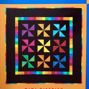 Peut inclure: Couverture de livre avec le titre "Borders & Bindings" en texte blanc sur fond bleu. Le livre fait partie d'une série intitulée "Your First Quilt Book : Basic Quiltmaking Techniques for". La couverture présente également un bloc de courtepointe coloré sur fond noir.