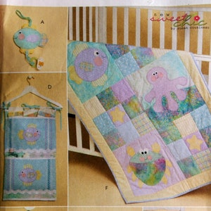 Puede incluir: Patrón de costura Sew Sweet Chic de Susan Cousineau para una colcha de bebé, un móvil de cuna y artículos de almacenamiento. El patrón incluye una variedad de diseños con temática marina, como peces, un pulpo y un cangrejo. El patrón está impreso en un fondo blanco con acentos azules y rosas.