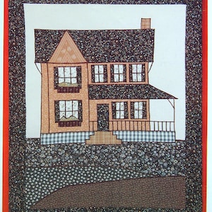 May include: A farmhouse wall hanging pattern with a finished size of 21" x 27". The design features a two-story house with a brown roof, tan walls, and a porch. The background is a mix of floral and dotted patterns.
