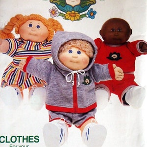May include: Vintage Cabbage Patch Kids doll clothes pattern. The pattern features three dolls, one with orange hair in a striped dress, one with brown hair in a gray sweatsuit, and one with black hair in a red outfit. The pattern is from Butterick.