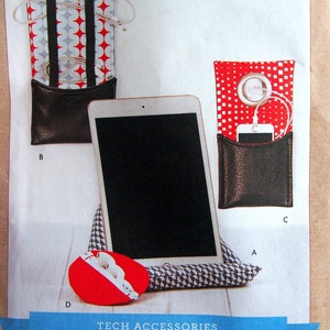 Peut inclure: Un patron de couture pour accessoires technologiques, comprenant une pochette à motif rouge et blanc avec un fond en cuir noir, une pochette pour téléphone à motif rouge et blanc avec un fond en cuir noir, un support de tablette à motif noir et blanc et une pochette rouge à motif blanc et gris. Le patron s'appelle "Kwik Sew" et le numéro du patron est "K4321".