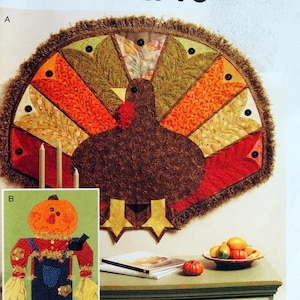 Puede incluir: Un patrón de costura para un pavo de Acción de Gracias y un espantapájaros. El pavo es un diseño de patchwork con un cuerpo marrón y plumas de colores. El espantapájaros es un diseño simple con una cabeza de calabaza, una camisa azul y pantalones marrones. El patrón es de McCall's Crafts y está etiquetado como M6413.