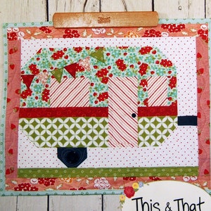 May include: A quilted wall hanging with a camper design in red, white, and green fabrics. The camper has a door, a wheel, and a button detail. The words "S'more Fun" and "This & That" are visible.