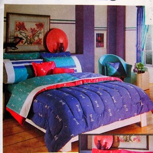 May include: A blue and white patterned bedding set with a red and white patterned pillow. The bedding is on a bed with a white frame. The bedding set is labelled "Gitano Environments".