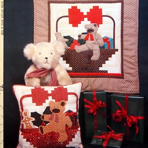 Peut inclure: Un patron de quilt vintage intitulé "Bear in a Basket" par Christal Carter. L'image présente un ours en peluche, un coussin avec un appliqué d'ours et des cadeaux emballés. Le patron comprend des instructions pour un coussin ou une tenture murale.