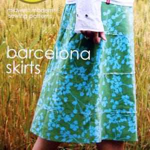 May include: A white ceramic mug with a black handle and the text "But First, Coffee" in a bold, black font. The mug is set against a blurred background, suggesting a cozy setting.