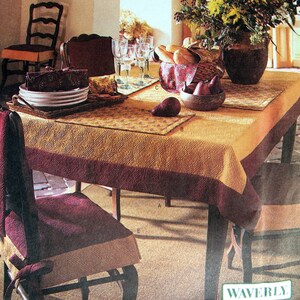 May include: A table setting with a yellow and brown tablecloth, a brown wooden table, and four chairs. The table is set with plates, silverware, and glasses. There is a basket of bread on the table, as well as a vase of flowers. The text "WAVERLY" is visible in the bottom right corner of the image.