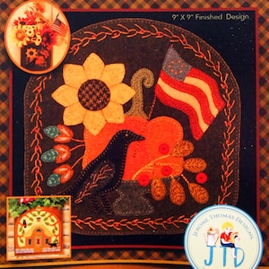 May include: A wool appliqué design kit titled "Autumn Glory." The design features a sunflower, pumpkin, crow, and American flag. The finished design measures 9" x 9". Also available from the series, "Little Pink Cottage."