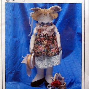 May include: A sewing pattern for a Tilly-Tat Stitcher doll. The doll is wearing a floral dress, a straw hat, and a necklace. The pattern is by Hollie Designs and is $4.50. The pattern number is DP 29.