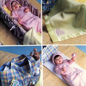 May include: A baby in a pink sleeper and matching hat is shown in a wicker bassinet. A green blanket with a yellow border and a plaid heart is also shown. A diaper bag with a plaid pattern and a baby with a rattle are also shown. The text "B4111 Butterick" is visible.