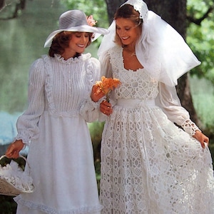 May include: Two women wearing white crochet wedding dresses. One woman is wearing a white hat and holding a basket of flowers. The other woman is wearing a veil and holding a bouquet of flowers.