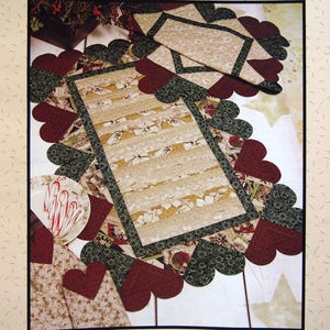 May include: A quilted table runner with a heart-shaped border and a rectangular center. The runner features a beige and cream striped pattern, with accents of red and green. The text "Heartfelt Table Runner" is at the top.
