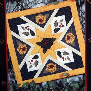 May include: A book titled "Seasonal Stars" by Nancy Odom, featuring a quilt pattern with a yellow star and floral designs. The book cover is black with a yellow banner at the top and a red banner at the bottom. The book is from Timid Thimble Creations.