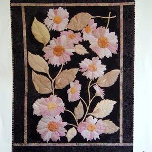 Peut inclure: Une œuvre d'art textile intitulée "White Daisy" par Laura Heine. L'œuvre présente des fleurs de marguerites roses et blanches avec des centres jaunes et des feuilles beiges sur un fond noir. Dimensions : 110.5 cm x 156.2 cm.