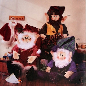 May include: McCall's Crafts pattern featuring three elf dolls. The dolls have white beards, rosy cheeks, and pointed ears. One elf wears a red outfit, another a yellow vest, and the third a purple outfit. The pattern number is 3837.