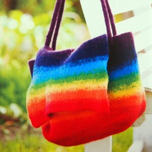 May include: A rainbow striped knitted tote bag with purple straps hanging on a white chair.