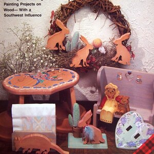 May include: A book cover with the title "Pickling for Beginners with Painted Accents" by Joey Williams. The cover features a painted wooden wreath, a painted wooden stool, a painted wooden bench, and a painted wooden heart. The book is about 22 different pickling and painting projects on wood with a southwest influence.