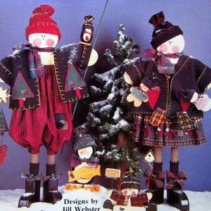 Puede incluir: Una escena invernal festiva con figuras de mu&ntilde;ecos de nieve hechas a mano. Los mu&ntilde;ecos de nieve visten chaquetas negras, pantalones rojos y bufandas a cuadros. La imagen incluye el texto "The Magic of the Season" y "Santa's Welcome."