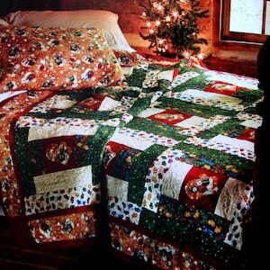 May include: A Christmas-themed quilt with red, green, and white squares, featuring a pattern of ornaments and lights. The quilt is on a bed with a pillow featuring a similar pattern. A small Christmas tree with lights is in the background.