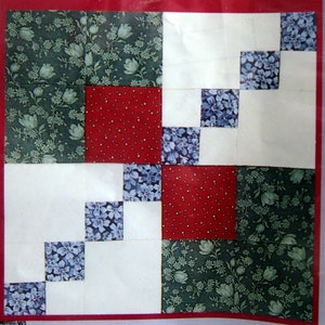 May include: A patchwork quilt block with the text "AUGUST 4-Patch Variation" at the top. The block features squares of white, red with white dots, blue floral, and green floral fabric.