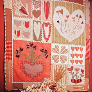 Peut inclure: Une courtepointe patchwork sur le thème du cœur. La courtepointe est faite de différents tissus dans des tons de rouge, rose et marron. La courtepointe est décorée de cœurs, de fleurs et d'autres motifs.