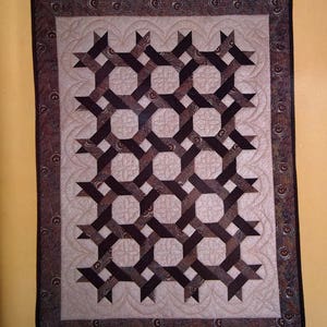 Peut inclure: Un livre de motifs de courtepointe avec un motif de courtepointe brun et blanc sur la couverture. Le titre est "Template-Free Quiltmaking" par Trudie Hughes. Le livre est de "That Patchwork Place".