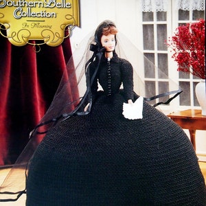 May include: A doll dressed in a black crocheted gown and veil, reminiscent of mourning attire. The doll is part of "The Southern Belle Collection" and holds a white handkerchief. The gown is floor-length and has a fitted bodice.
