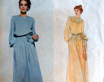 May include: Vogue American Designer pattern featuring a light blue dress with long sleeves, a tie waist, and a pleated skirt. Next to it is a sketch of a long, yellow dress with a belt and tassel. The text "VOGUE AMERICAN DESIGNER" is at the top, and "BILL BLASS" is at the bottom.