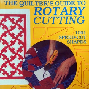 May include: A book titled The Quilter's Guide to Rotary Cutting with 1001 Speed-Cut Shapes by Donna Poster. The yellow cover features a red and white quilt pattern, geometric outlines, and a circular inset showing a rotary cutter on a blue mat.