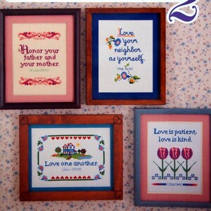 May include: Four framed cross-stitch patterns with Christian themes. The top left frame says "Honor your father and your mother. (Exod. 20/12)". The top right frame says "Love your neighbor as yourself. (Matt. 19:10)". The bottom left frame says "Love one another. (John 13:34)". The bottom right frame says "Love is patient, love is kind. (1 Cor. 13:4)".