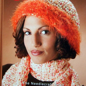 May include: A crochet book titled "Warm & Fuzzy Crochet" edited by Bobbie Matela. The cover features a woman wearing a crocheted hat and scarf in shades of orange and white.