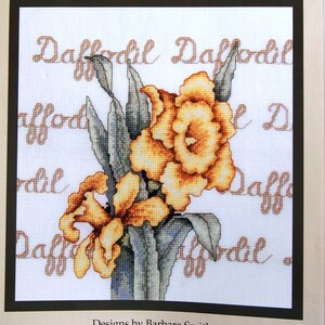 Könnte beinhalten: Gezähltes Kreuzstichmuster für ein Narzissenblumenmotiv. Das Muster zeigt zwei gelbe Narzissen mit grünen Blättern und dem Text "Daffodil Daffodil" in braunen Buchstaben. Das Muster ist von Bobbie G. Designs und trägt den Titel "Daffodil" mit der Nummer #D0525. Die fertige Größe beträgt 8,5 Zoll mal 9,5 Zoll.