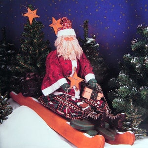 May include: A folk art Santa doll on skis, part of the "Winter-Thyme" series. The doll wears a red coat and hat with white trim, holding a star and gifts. The skis are orange, and the background features evergreen trees and a starry sky.