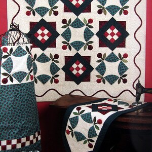 Peut inclure: Une courtepointe intitulée "Cherry Pie Quilt", avec un fond blanc et un motif répété de cerises rouges et vertes, de feuilles et un losange avec un motif à carreaux rouge et blanc. La courtepointe est encadrée d'une bordure ondulée rouge foncé.