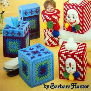 May include: A vintage book cover featuring handmade bathroom boxes in plastic canvas. The boxes are in various colors and designs, including blue, red, and white, with decorative elements. The text reads "Bathroom Boxes in plastic canvas" and "by Barbara Hunter."