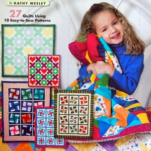 Op de afbeelding: Een boek getiteld "Quilts for Kids to Love" van Kathy Wesley, met een jong meisje dat een kleurrijke quilt vasthoudt. De omslag van het boek toont 27 quilts met 10 gemakkelijk te naaien patronen.