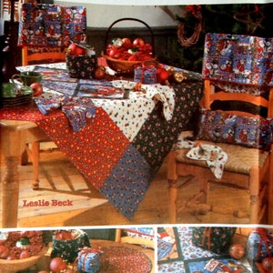 May include: A Christmas table setting featuring a red, white and blue patchwork tablecloth, matching placemats and napkins. The table is decorated with a basket of red baubles, a bowl of red baubles, and a selection of Christmas-themed gifts. The chairs are covered in festive fabric with a Christmas theme.