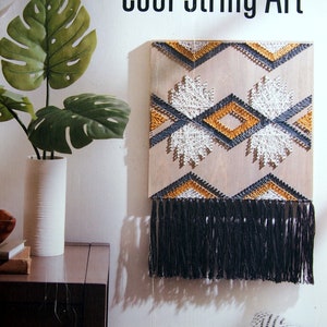 Op de afbeelding: Cool String Art door Lori Wenger, een boekomslag met een geometrisch string art-ontwerp met zwarte, witte en gouden draden op een houten achtergrond.