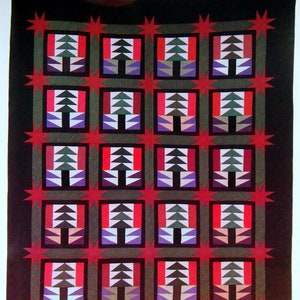 May include: A handmade quilt featuring a repeating pattern of stylised trees and star shapes. The trees are green, white, and purple, set against red and black squares. The quilt's border has red star shapes on a black background.