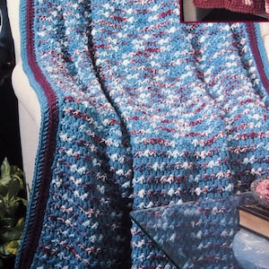 May include: The cover of a crochet pattern book, "Quick Crochet AFGHANS Book 4" by Leisure Arts. It shows a blue, white, and red crocheted blanket and a smaller image of a pink crocheted afghan. The text "Featuring Variegated Yarn Designs by Shala Johnson" is also visible.