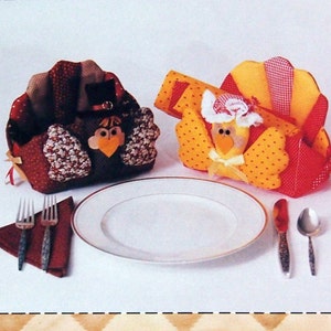 May include: Two Thanksgiving turkey napkin holders, one red and brown, the other yellow and red, with a white plate and silverware on a white background. The text "Patch Press" and "Napkin Holder" is visible on the image.