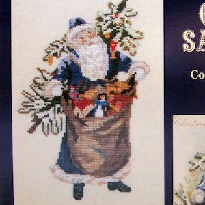 May include: A cross-stitch pattern titled Sew Fine Presents L-22 Olde Santas Collection IX 1906 Toy Bag Santa. The image features a cross-stitched Santa in a blue coat carrying a large brown sack filled with toys and a small tree, alongside a vintage illustration.