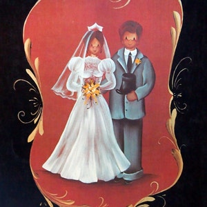May include: A vintage painting titled "All The Sweet Things" depicting a bride and groom. The bride is in a white dress and veil, holding flowers. The groom wears a grey suit and holds a hat. The painting is set against a red heart-shaped background with gold detailing.