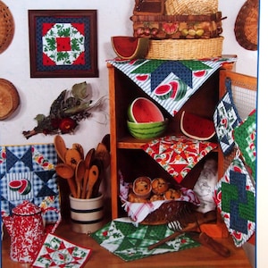 May include: A book cover titled "Quilt Block Pot Holders" with a green and white design. The image showcases various quilted pot holders, watermelon-themed decor, and a framed quilt block. The text reads "48 Quilt Block Favorites You'll Love to Stitch!"