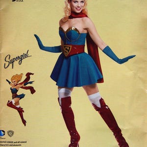 May include: A Simplicity sewing pattern featuring a DC Comics Bombshells Supergirl costume. The costume includes a blue dress, red cape, gloves, and boots. The pattern is size U.S. 6-14.