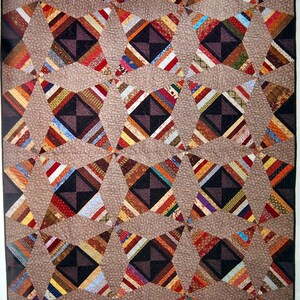 May include: A quilt with a geometric pattern of brown, red, and white stripes. The quilt is made up of many small squares and triangles, and the pattern is repeated throughout the quilt.