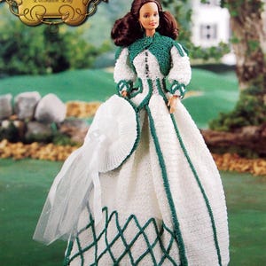 May include: A doll from "The Southern Belle Collection" wearing a white dress with green trim and a matching bolero jacket. The doll is holding a white fan and has brown hair. The text "Decoration Day" is visible.