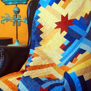 May include: A blue, yellow, orange, and red patchwork quilt with a star design. The quilt is draped over a black leather armchair.
